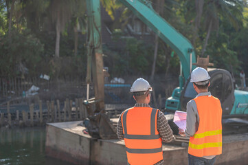 Construction engineer working on a bridge construction site over a river,Civil engineer supervising work,Foreman inspects work at a construction site,Discuss technical problems together