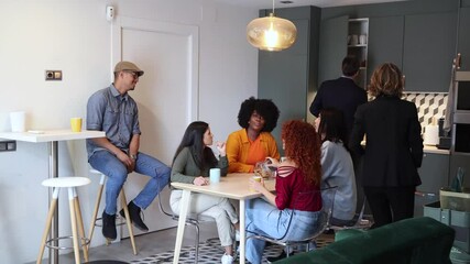 Office coworkers chatting and drinking coffee in the break area during free time.