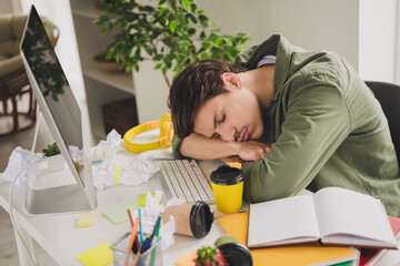 Photo of bored sleepy man lying table hard work workstation workspace indoors