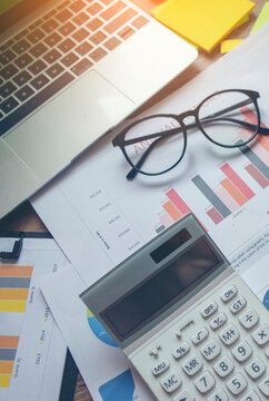 Business computer office wooden desk with annual report, summary report, document, paper, calculator, cup of coffee, and working space. Business executive office desk concept-vertical image.