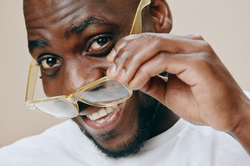 Happy joyful man adjusting glasses, smiling brightly showcasing positive emotions, wearing casual...