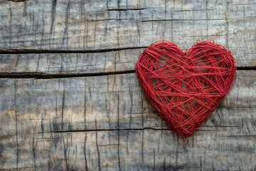 Fototapeta premium Handmade red yarn heart on weathered wooden background
