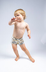 A young toddler plays on a white backdrop in a photo studio.