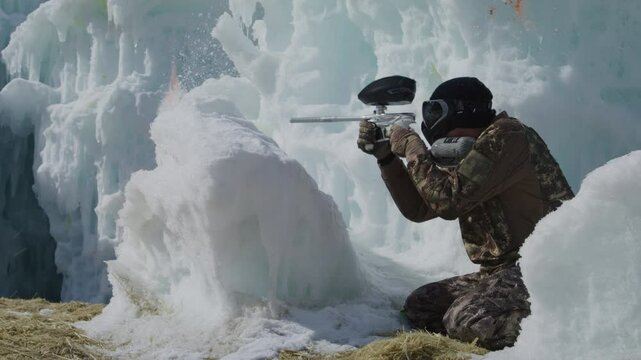 Paintballer behind ice mound, shooting and being shot at - cinematic slow motion