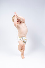 A young toddler plays on a white backdrop in a photo studio.