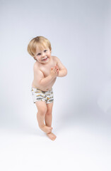 A young toddler plays on a white backdrop in a photo studio.