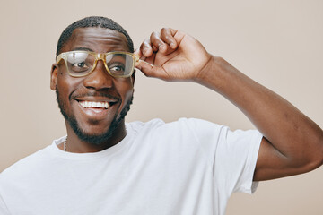 Smiling young man wearing glasses, casual white t shirt, joyful expression, light beige background,...