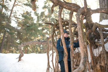 The boy walks through the snow-covered forest and enjoys the beauty of the winter landscape.