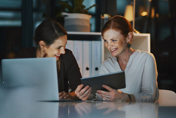 Office, women and happy at night with technology for online research on deadline or overtime for project. People, employees and laptop or tablet for teamwork, collaboration and coworking for business