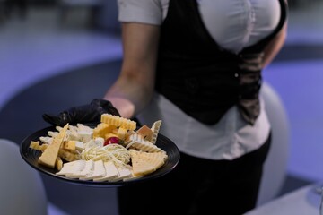 Waiter serving assorted cheeses in a restaurant.