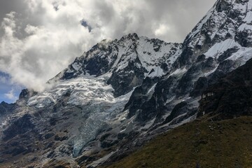 Stunning view of the snow-capped Salkantay Mountain peak with clouds against a clear blue sky.