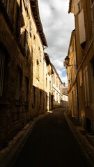 Obraz premium Narrow street in a historic European town with stone buildings and a cloudy sky