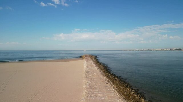 Aerial of Atlantic Ocean with sandy beach on a sunny day with blue sky in Trafaria, Lisbon, Portugal