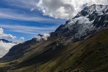 Fototapeta premium Stunning view of the snow-capped Salkantay Mountain peak with clouds against a clear blue sky.