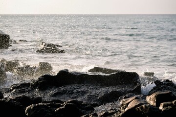 Waves crashing on black volcanic rocks at the shoreline.