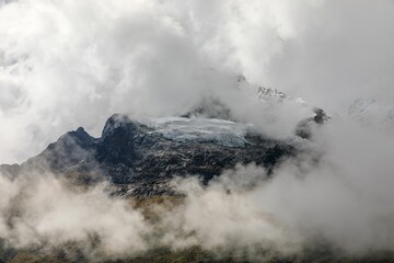 Stunning view of the snow-capped Salkantay Mountain peak with clouds against a clear blue sky.