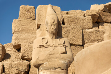 Statues of Osiris with the key of life are a prominent feature of the Karnak Temple in Luxor, Egypt. This imposing figure stands guard at the entrance of the temple, welcoming visitors.