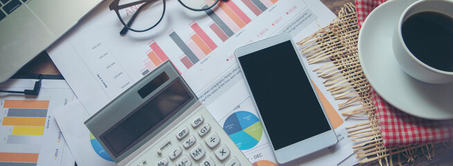 Business desk and office workspace with calculator, financial reports, laptop, glasses, smartphone,...