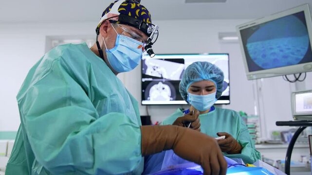 Surgeon extracts the deleted piece from the nasal cavity of a patient. Doctor and scrub nurse perform otolaryngology operation in the modern surgery room.