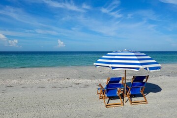 Beach umbrellas with chairs in the sand on the beach.