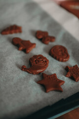 Raw gingerbread cookies in festive shapes like stars, Christmas trees and gingerbread men are placed on parchment paper.