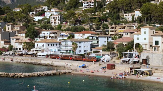 Sunny Aerial View of Historic Port de Soller Tram with Tourists in Mallorca