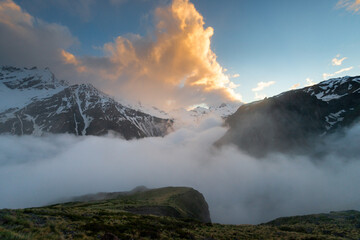 Beautiful view of the harsh snowy peaks of the Elbrus mountains at sunset with low clouds. The North Caucasus. Russia.