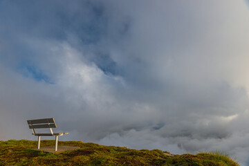 A picturesque harsh landscape with a bench on the edge of a cliff against the background of...