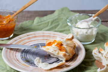 Plate with bread spread with jam and cream cheese and bowls with ingredients.