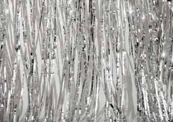Shiny metallic silver background with crumpled, textured foil pattern. Reflective surface with light and wrinkles, creating an abstract and bright design. Perfect for holiday