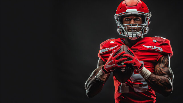 American football player in a red jersey and helmet holding a ball against a black background.