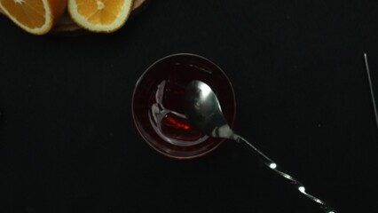 Top down view of bartender hand making and prepare Scarlet spritzer with black background. Close up of smart bartender hands presenting and making red cocktail with lemon slice decorated. Comestible.