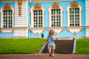 Little girl child walks to Catherine's Park with a palace, family tourism, active childhood.