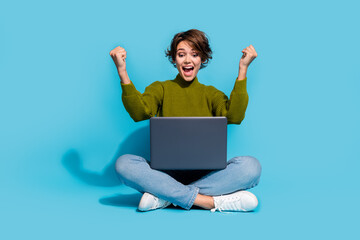 Photo of overjoyed glad lovely girl wear stylish clothes sitting floor celebrate victory shout yes isolated on cyan color background