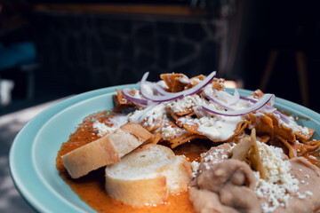 Platillo Mexicano chilaquiles con carne de puerco acompañado de frijoles y pan