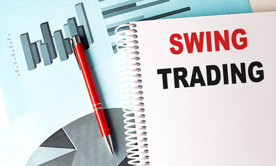 Swing trading concept with financial charts, notepad, and red pen on a desk
