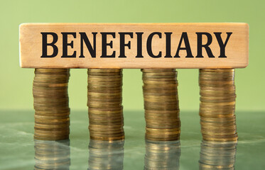 BENEFICIARY - word on a wooden block on a background of stacks of coins