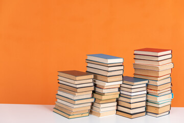 Old vintage stacks of books to read on an orange background