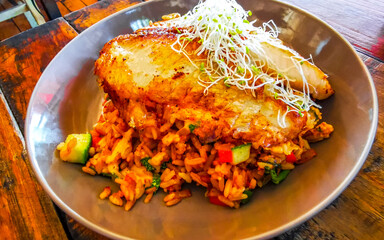 Grilled fish on rice vegetables and chipotle sauce dish meal.