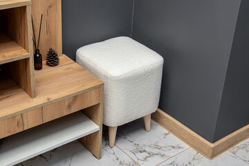 Square pouf with wooden legs. White pouf in hallway