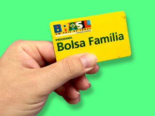 Cartão bolsa familia do governo não mão de uma pessoa com fundo branco.