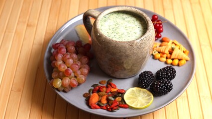 Plate with seasonal fruits, and juice on wood table offers refreshing, nutrient-rich meal. Emphasizing clean, plant-based eating with focus on sustainable, eco-conscious nutrition.