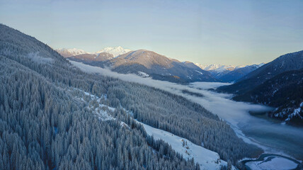 Obraz premium A breathtaking aerial view of a snow-covered valley surrounded by mountain ranges.