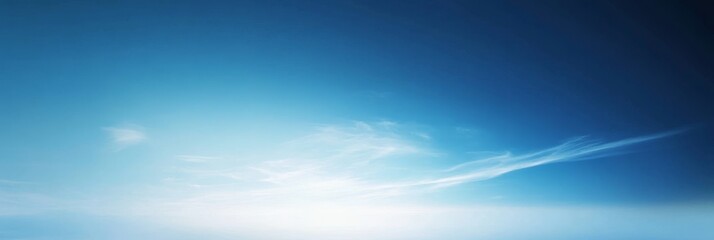 Obraz premium A stunning image of a serene blue sky with delicate, white clouds transitioning from a light to a deep blue gradient. The clouds create a sense of peace and tranquility, symbolizing hope, freedom, and