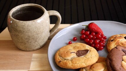 Sleek grey plate of biscuits and cup of tea make for perfect eco-luxury breakfast. Paired with fresh berries, this elegant setup is both stylish and sustainable, offering refined start to your day.