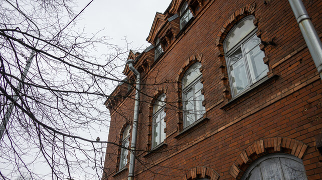 A brick building with arched windows and a tree in front