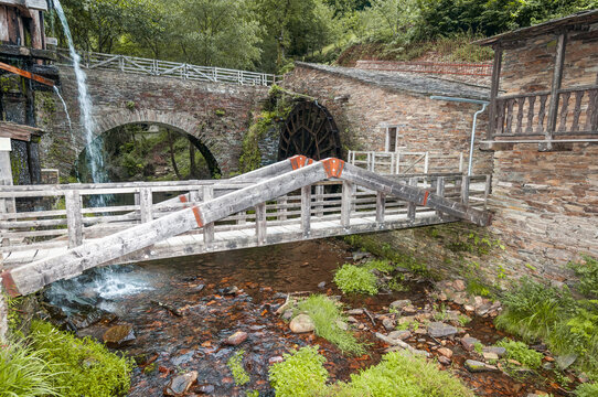 Historic water mill with flowing waterfall and stone bridge