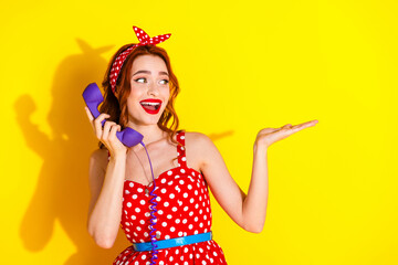 Photo of pretty cute nice lady wear red stylish dress speak phone presenting empty space isolated on yellow color background