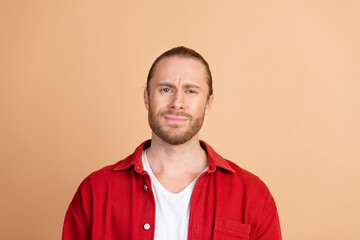 Portrait of nice young man think doubt wear red shirt isolated on beige color background