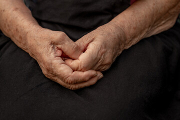 Aged hands of an elderly woman on a black background